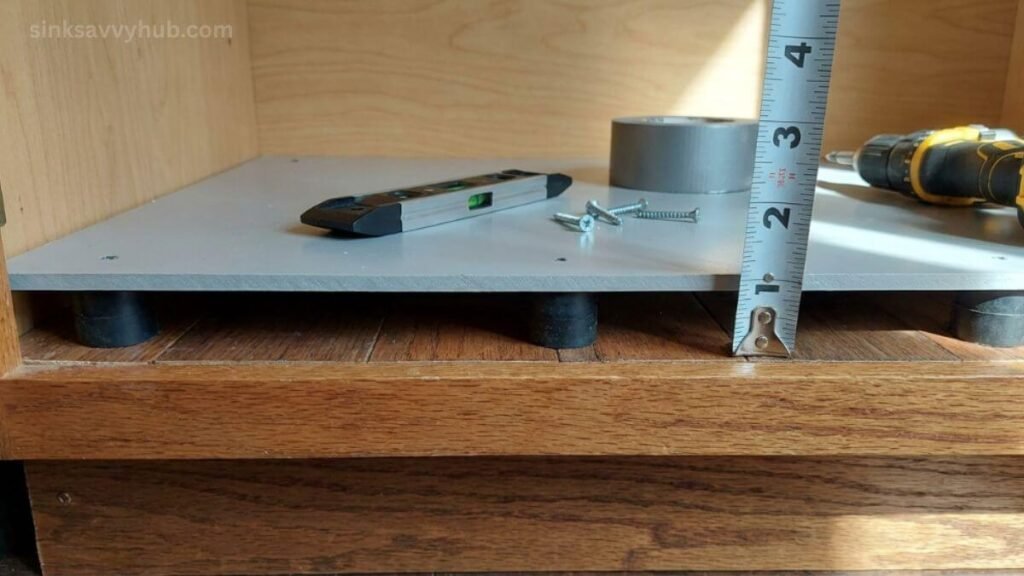 false bottom floor setup under kitchen sink A hard PVC false bottom floor raised on rubber feet to protect the under-sink cabinet base from water damage
