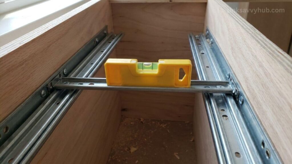 leveling sliding drawer tracks under sink Using a small level tool on sliding tracks to ensure a perfectly flat and smooth drawer installation